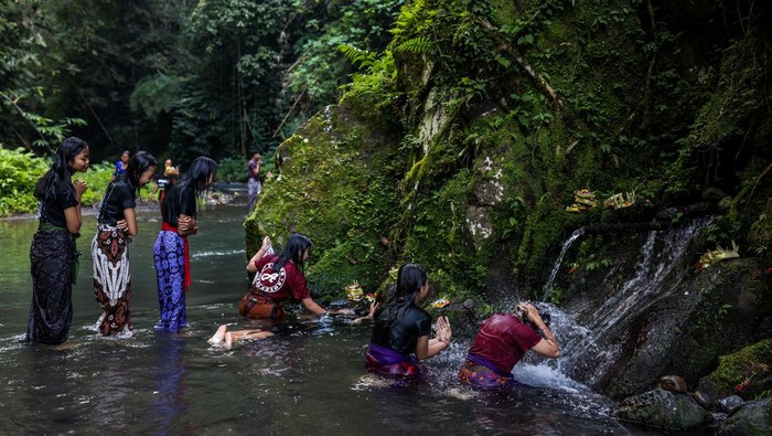 An offering is pictured as Balinese Hindus (background) perform ritual called Melukat to celebrate Banyu Pinaruh in Bebalang Village, Bangli Regency, Bali, Indonesia, on May 21, 2023. Banyu Pinaruh is a ritual for self-cleansing performed by Balinese Hindus after celebrate Saraswati Day, a day to worship a Goddess of Knowledge. Devotees bathe in the holy water of a spring, waterfall, or any other water source belived to have the apropriate cleansing power for purification. The ritual is a symbolical and literal cleansing of the body and soul aimed at preventing misfortune, sickness or havoc caused by daily activities and sins. (Photo by Garry Lotulung/NurPhoto via Getty Images)