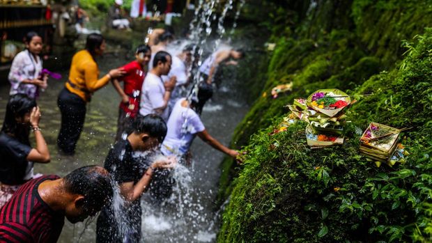 An offering is pictured as Balinese Hindus (background) perform ritual called Melukat to celebrate Banyu Pinaruh in Bebalang Village, Bangli Regency, Bali, Indonesia, on May 21, 2023. Banyu Pinaruh is a ritual for self-cleansing performed by Balinese Hindus after celebrate Saraswati Day, a day to worship a Goddess of Knowledge. Devotees bathe in the holy water of a spring, waterfall, or any other water source belived to have the apropriate cleansing power for purification. The ritual is a symbolical and literal cleansing of the body and soul aimed at preventing misfortune, sickness or havoc caused by daily activities and sins. (Photo by Garry Lotulung/NurPhoto via Getty Images)