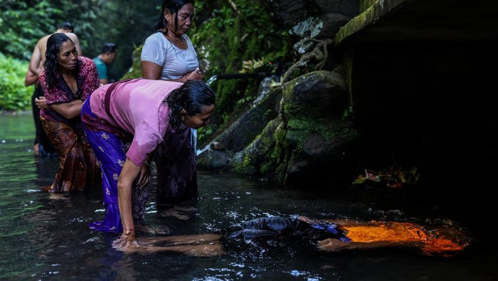 An offering is pictured as Balinese Hindus (background) perform ritual called Melukat to celebrate Banyu Pinaruh in Bebalang Village, Bangli Regency, Bali, Indonesia, on May 21, 2023. Banyu Pinaruh is a ritual for self-cleansing performed by Balinese Hindus after celebrate Saraswati Day, a day to worship a Goddess of Knowledge. Devotees bathe in the holy water of a spring, waterfall, or any other water source belived to have the apropriate cleansing power for purification. The ritual is a symbolical and literal cleansing of the body and soul aimed at preventing misfortune, sickness or havoc caused by daily activities and sins. (Photo by Garry Lotulung/NurPhoto via Getty Images)