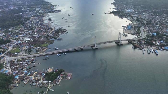 Sejumlah warga duduk dengan latar belakanbg Jembatan Teluk Kendari di Kendari, Selasa (23/5/2023). Pembangunan Jembatan Teluk Kendari sepanjang 1.380 meter tersebut memberikan dampak positif seperti kelancaran lalu lintas dan memicu tumbuhnya aktivitas perekonomian antara kabupaten-kabupaten yang menghubungkan ke pusat Kota Kendari sehingga berdampak pada pertumbuhan produk domestik regional bruto. ANTARA FOTO/Jojon/tom.