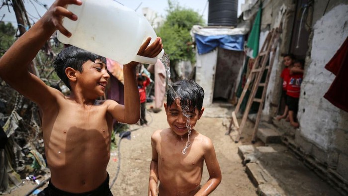 Gelombang panas tengah melanda Palestina, terutama di Kota Gaza. Warga yang terdiri anak-anak di daerah kumuh di Gaza mengguyur tubuhnya dan mandi di depan rumah.