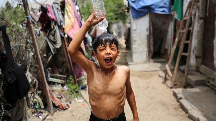 Gelombang panas tengah melanda Palestina, terutama di Kota Gaza. Warga yang terdiri anak-anak di daerah kumuh di Gaza mengguyur tubuhnya dan mandi di depan rumah.