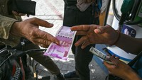 Seorang pelanggan menyerahkan uang kertas 2.000 rupee kepada petugas di pom bensin di New Delhi, India, Selasa (23/5/2023).