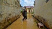 Seorang warga membawa kasur melewati samping rumahnya yang terendam banjir di Kenali Asam Bawah, Kota Baru, Jambi, Selasa (23/5/2023).