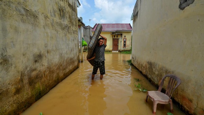Jalanan di Jambi Terendam Banjir Gegara Sistem Drainase Kurang Berfungsi Seorang warga membawa kasur melewati samping rumahnya yang terendam banjir di Kenali Asam Bawah, Kota Baru, Jambi, Selasa (23/5/2023). Banjir akibat kurang berfungsinya sistem drainase setelah hujan deras pada Selasa (23/5) dini hari mengakibatkan seratusan rumah dan beberapa ruas jalan di kota itu terendam air hingga ketinggian setengah meter. ANTARA FOTO/Wahdi Septiawan/tom.