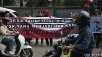 Pengendara melintas di depan massa yang tengah beraksi.