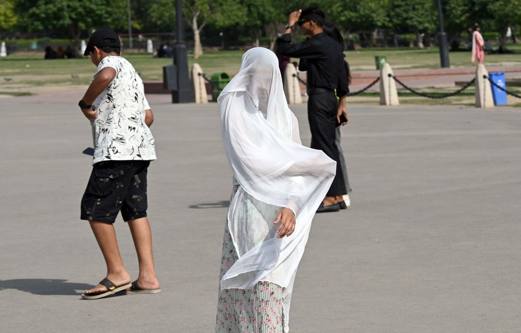 Orang-orang keluar di Gerbang India pada sore yang panas, pada 21 Mei 2023 di New Delhi, India. (Sanjeev Verma/Hindustan Times via Getty Images)