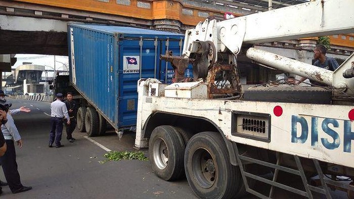 Proses evakuasi truk kontainer nyangkut di jembatan  rel kereta api di kawasan Gunung Antang, Matraman (dok. Instagram @tmcpoldametro)