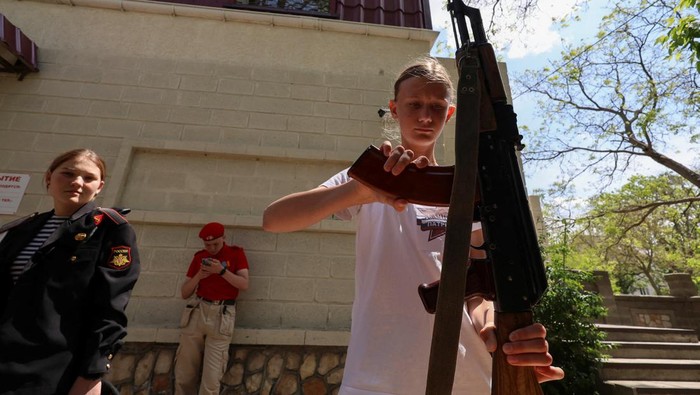 Rusia Beri Latihan Militer ke Anak-anak Sekolah di Crimea Members of Russia's Youth Army military-patriotic movement and other participants attend a demonstration lesson that is part of an extracurricular educational program, which involves weapon training, first aid treatment, camping skills and other courses, in Sevastopol, Crimea, May 19, 2023. REUTERS/Alexey Pavlishak