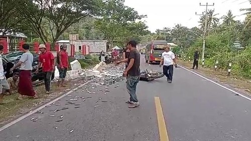Kondisi lokasi kecelakaan sepeda motor dan mobil terpental dan ikan berserakan di jalan.