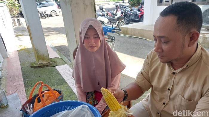 Diana saat melayani pembeli jagung rebusnya.