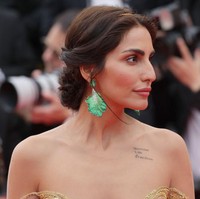 Namun yang membuat penampilannya mencuri perhatian bukan karena busananya. Melainkan tato di bahunya yang bertuliskan Women, Life, Freedom. Foto: Getty Images