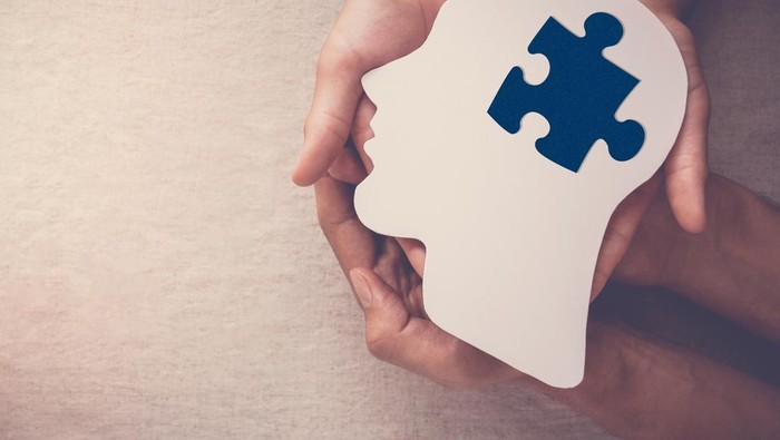 hands holding puzzle piece missing in brain paper cutout, autism, dementia, mental health concept