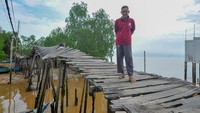 Warga berdiri di ujung jembatan yang rusak di Tanjung Solok, Tanjung Jabung Timur, Jambi, Rabu (24/5/2023).  