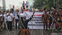 Dalam aksinya, terlihat dua orang mengenakan koteka atau baju khas Papua.