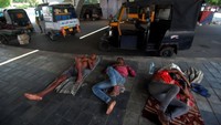 Pengemudi becak otomatis dan becak terlihat sedang beristirahat di jembatan layang saat mereka mengundurkan diri dari pekerjaan mereka di siang hari yang panas karena gelombang panas di ibu kota negara bagian Odisha, Bhubaneswar, India timur. STR/NurPhoto/Getty Images  