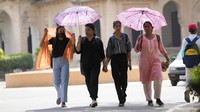 Mahasiswa Universitas Allahabad memegang payung saat mereka berjalan di sore yang panas di Prayagraj, Uttar Pradesh. Saat suhu melewati 45 derajat Celcius (113 derajat Fahrenheit) di negara bagian utara ini, beberapa bagian mengalami pemadaman listrik yang berlangsung lebih dari 12 jam. AP/Rajesh Kumar Singh  