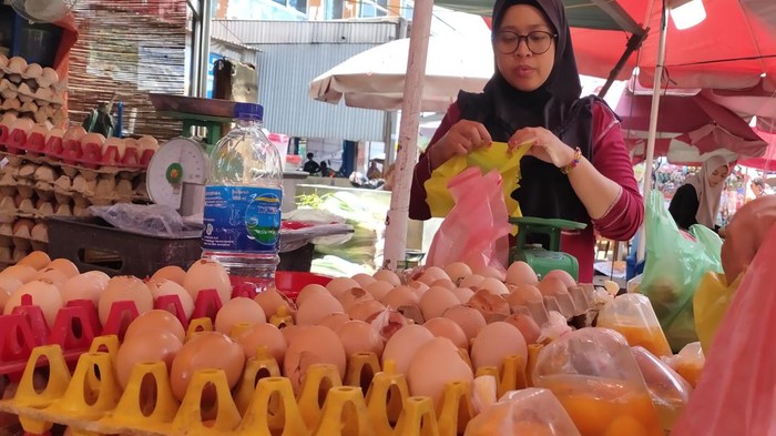 Salah seorang pedagang di Palembang membeli telur retak di pasar menyiasati harga telur utuh yang mahal. (Welly Jasrial/detikSumbagsel)