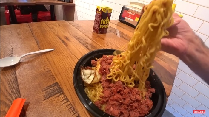 Bule mencoba Indomie goreng dengan topping kornet dan telur di warkop New York, Amerika Serikat