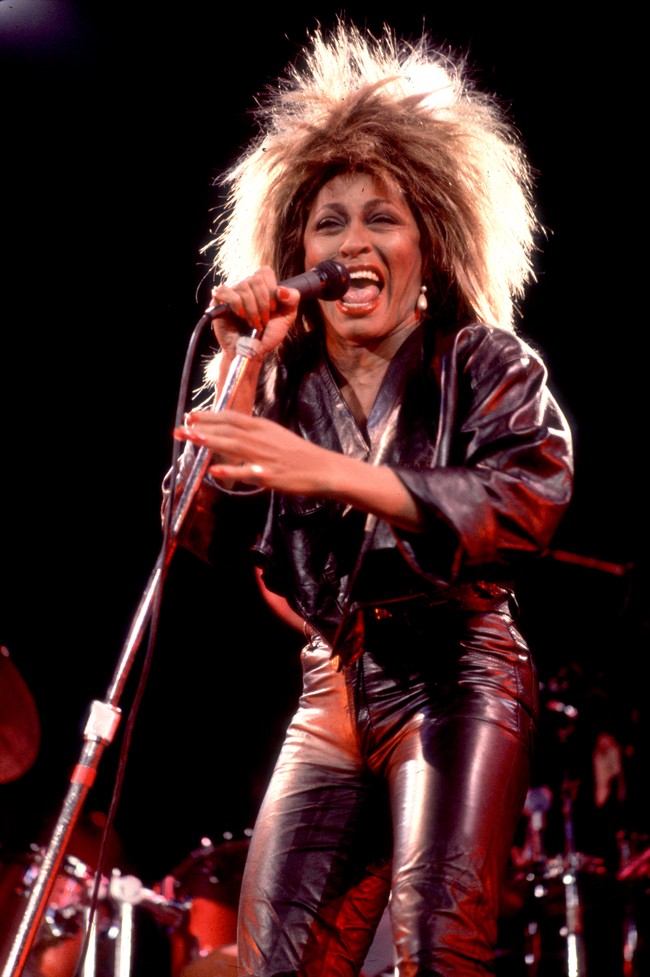 Gaya Tina Tuner mulai bertransisi lagi pada era 80-an. Rambut megar serta dress kulit berpadu denim semakin mempertegas statusnya sebagai ratu rock n roll. (Foto: Paul Natkin/Getty Images)