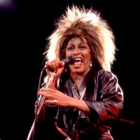 Gaya Tina Tuner mulai bertransisi lagi pada era 80-an. Rambut megar serta dress kulit berpadu denim semakin mempertegas statusnya sebagai ratu rock n roll. (Foto: Paul Natkin/Getty Images)