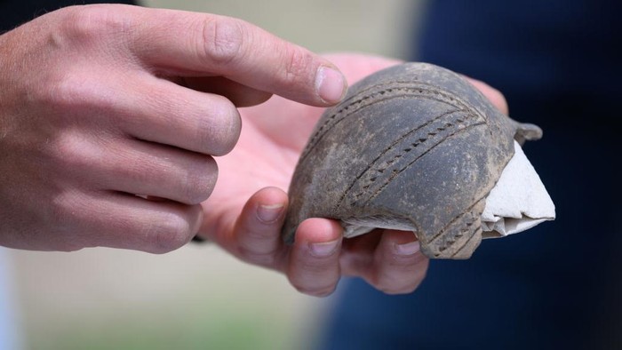 Potret Ekskavasi Makam Era Neolitik dari 5.500-4.500 SM di Jerman 24 May 2023, Saxony, DΓΆbeln: An employee of the Saxony State Office for Archaeology holds a part of a bottle from the Linear Pottery (ca. 5500-4900 BC) during excavations on the construction site of the future