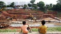 Dua orang anak melihat proses pembangunan sodetan dari pinggir sungai. Sementara alat berat berupa ekskavator terlihat sibuk melakukan pengerukan.  