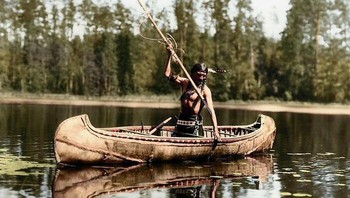 Seorang penduduk asli Amerika, Suku Ojibwe,tengah menombak ikan di sebuah danau yang berada di Minnesota, Amerika Serikat. Foto diambil pada tahun 1908. Foto: Boredpanda