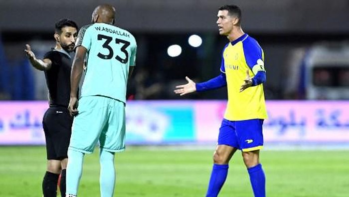 Nassr's Portuguese forward Cristiano Ronaldo (R) and Nassr's Saudi goalkeeper Waleed Abdullah (C) talk to an assistant referee during the Saudi Pro League football match between Al-Nassr and Al-Ettifaq at the Prince Mohammed Bin Fahd Stadium in Dammam on May 27, 2023. (Photo by AFP)