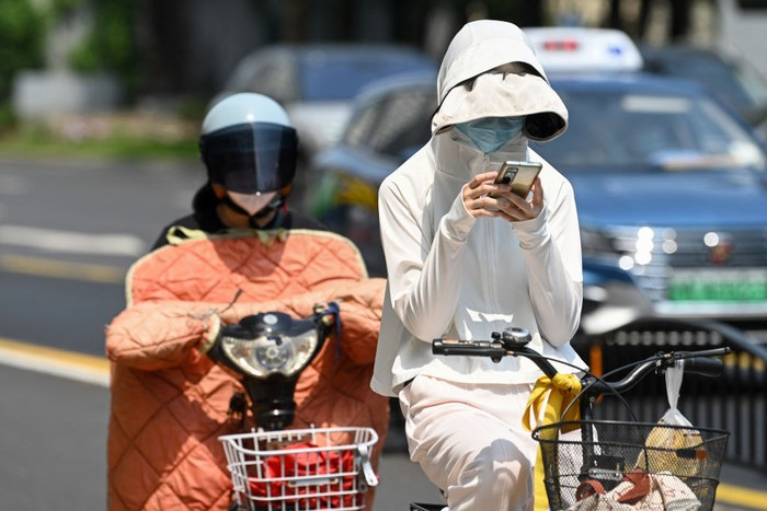 A woman wearing sun protective clothing walks along a street amid hot weather in Shanghai on May 29, 2023. Shanghai on May 29 recorded its hottest May day in 100 years, the citys meteorological service announced, shattering the previous high by a full degree. (Photo by AFP) / China OUT (Photo by STR/AFP via Getty Images)