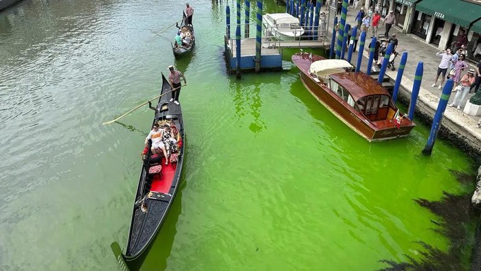 A bright patch of green is seen in the Grand Canal along an embankment lined with restaurants, in Venice, Italy, Sunday, May 28, 2023. Police in Venice are investigating the source of a phosphorescent green liquid patch that appeared Sunday in the citys famed Grand Canal. (AP Photo/Luigi Costantini)