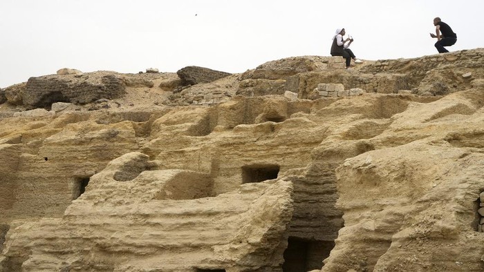 Visitors pose for pictures on top of recently unearthed ancient embalming workshops at the site of the Step Pyramid of Djoser in Saqqara, 24 kilometers (15 miles) southwest of Cairo, Egypt, Saturday, May 27, 2023. Saqqara is a part of Egypt's ancient capital of Memphis, a UNESCO World Heritage site. (AP Photo/Amr Nabil)
