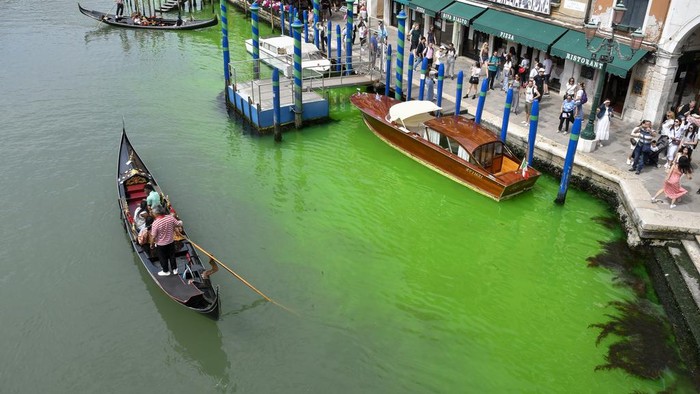 Gondolas navigate by the Rialto Bridge on Venices historical Grand Canal as a patch of phosphorescent green liquid spreads in it, Sunday, May 28, 2023. The governor of the Veneto region, Luca Zaia, said that officials had requested the police to investigate to determine who was responsible, as environmental authorities were also testing the water. (AP Photo/Luigi Costantini)