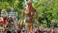 Tampak sebuah patung besar Karneval Für Die Zukunft diangkat di atas kerumunan selama parade tahunan Karnaval Budaya.  