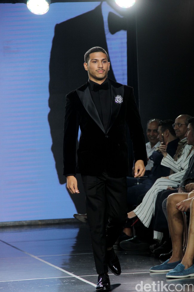 Tuksedo serbah hitam menemani gaya aktor Denzel Jordan Pangeran di catwalk. Penampilannya dilengkapi bros yang dirancang oleh desainer aksesori ternama Rinaldy A. Yunardi. (Foto: Abduh/Detikcom)