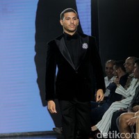 Tuksedo serbah hitam menemani gaya aktor Denzel Jordan Pangeran di catwalk. Penampilannya dilengkapi bros yang dirancang oleh desainer aksesori ternama Rinaldy A. Yunardi. (Foto: Abduh/Detikcom)