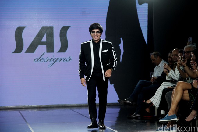 Tentunya tidak ketinggalan Atta Halilintar yang jas pernikahannya dulu dirancang oleh SAS Designs. Kali ini, ia memeragakan busana formal serba hitam yang dipadu jas bergaya athleisure dengan aksen putih. Headband khas Atta tetap jadi andalan. (Foto: Abduh/Detikcom)