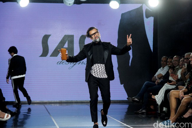 Deretan selebriti pria ternama muncul sebagai model di catwalk peragaan tersebut. Salah satunya Jeremy Thomas yang memeregakan setelan serba hitam dengan kemeja bergaya tuksedo yang bagian bawah dihiasi barisan nama ‘SAS’. Sepatu formal tanpa kaus kaki memberi kesan yang modern. (Foto: Abduh/Detikcom)