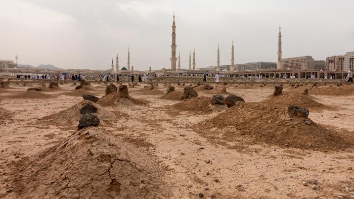 Ancient graves in Jannat Al Baqi Cemetery and the Prophets Mosque al Masjid an Nabawi at the background in Medina, Saudi Arabia