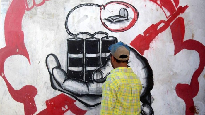 Seniman Jalanan Yaman Kisahkan Perang di Reruntuhan Bangunan TOPSHOT - In this picture taken on May 10, 2023, Yemeni street artist Alaa Rubil finishes one of his artworks painted on a wall in the southern port city of Aden. Rubil uses the shell-pocked buildings of his hometown as canvas, painting images of death and despair to shine a light on the horrors and victims of war. Not long after the start of the bloody war between Yemen's internationally recognised government and Huthi rebel forces, the 30-year-old artist's home of Aden became the scene of brutal fighting. (Photo by Saleh Al-OBEIDI / AFP) (Photo by SALEH AL-OBEIDI/AFP via Getty Images)