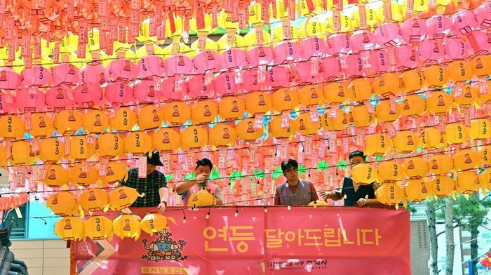 Warna-warni Lentera Sambut Ulang Tahun Buddha di Korea Selatan TOPSHOT - A worker attaches name cards with wishes of Buddhist followers to lotus lanterns at Jogyesa Temple in Seoul on May 26, 2023, ahead of celebrations marking Buddha's birthday on May 27. (Photo by Jung Yeon-je / AFP) (Photo by JUNG YEON-JE/AFP via Getty Images)