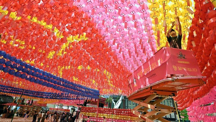 TOPSHOT - A worker attaches name cards with wishes of Buddhist followers to lotus lanterns at Jogyesa Temple in Seoul on May 26, 2023, ahead of celebrations marking Buddha's birthday on May 27. (Photo by Jung Yeon-je / AFP) (Photo by JUNG YEON-JE/AFP via Getty Images)