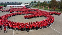 Para pesepeda yang menggunakan kostum serba merah ini berdiri membentuk sepeda.