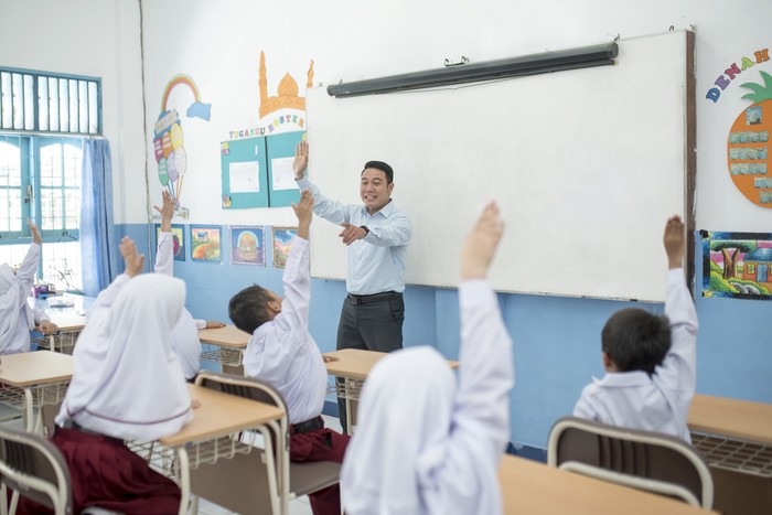 Students raise their hands to answer questions in class.