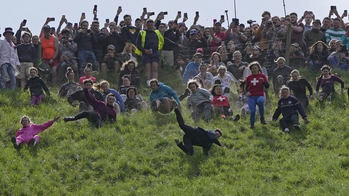 Participants compete in the women's downhill race during the Cheese Rolling contest at Cooper's Hill in Brockworth, Gloucestershire, Monday May 29, 2023. The Cooper's Hill Cheese-Rolling and Wake is an annual event where participants race down the 200-yard (180 m) long hill chasing a wheel of double gloucester cheese. (AP Photo/Kin Cheung)