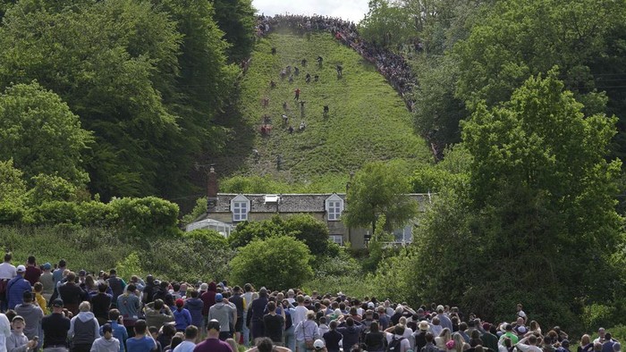 Participants compete in the women's downhill race during the Cheese Rolling contest at Cooper's Hill in Brockworth, Gloucestershire, Monday May 29, 2023. The Cooper's Hill Cheese-Rolling and Wake is an annual event where participants race down the 200-yard (180 m) long hill chasing a wheel of double gloucester cheese. (AP Photo/Kin Cheung)