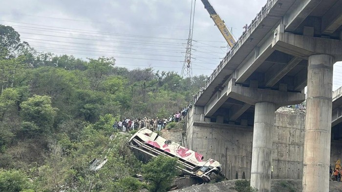 A rescue operation team inspects the wreckage of a bus after an accident near Jammu, India, Tuesday, May 30, 2023. The bus carrying Hindu pilgrims to a shrine in Indian-controlled Kashmir skidded off a highway bridge into a Himalayan gorge, killing at least 10 people and injuring 55, police said. (AP Photo/Channi Anand)
