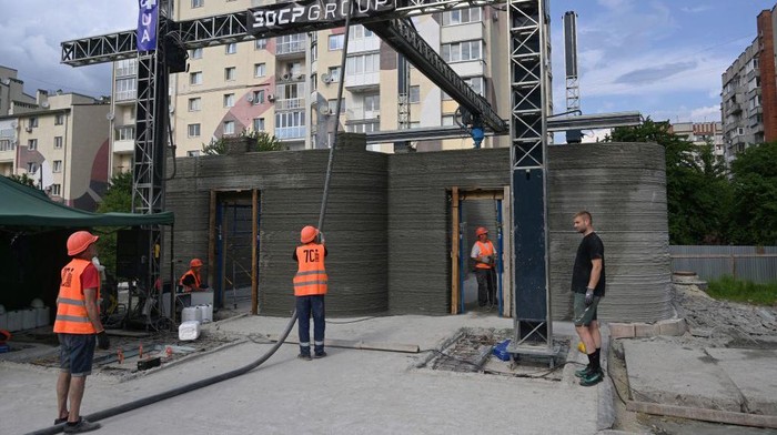 Melihat Proyek Sekolah Ukraina Dibangun dengan Mesin Cetak 3D People work at a construction site of a school in Ukraine, using concrete 3D printing technology, in the western Ukrainian city of Lviv, on May 24, 2023. (Photo by YURIY DYACHYSHYN / AFP) (Photo by YURIY DYACHYSHYN/AFP via Getty Images)