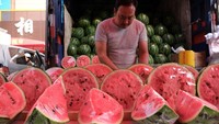 Penjual menjajakan buah semangka di atas meja.