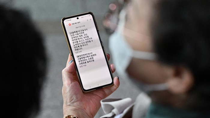 A woman shows her mobile phone with an emergency evacuation warning text message issued by Seoul City at the Seoul Railway Station in Seoul on May 31, 2023. North Korea launched its purported spy satellite on May 31, the Souths military said, prompting confusion in Seoul as the city briefly issued an evacuation warning in error. (Photo by Jung Yeon-je / AFP)